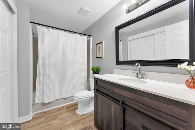 bathroom with visible vents, toilet, shower / bath combo, vanity, and wood finished floors