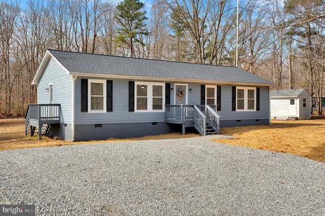 view of front facade featuring crawl space, roof with shingles, a shed, and an outbuilding