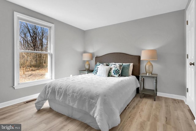 bedroom featuring baseboards, visible vents, and light wood-style floors