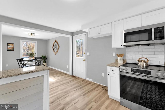 kitchen with white cabinets, light stone countertops, and stainless steel appliances