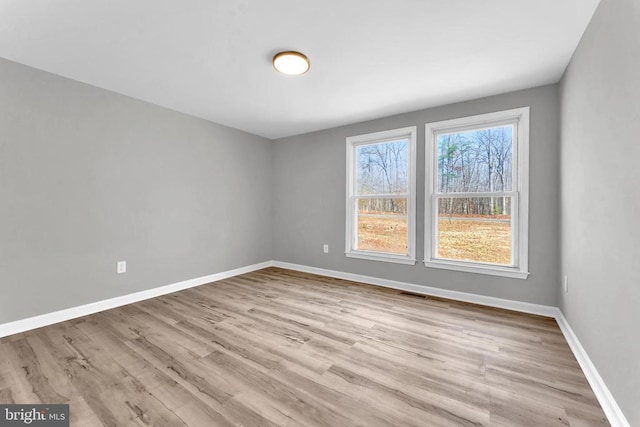 unfurnished room with visible vents, light wood finished floors, and baseboards