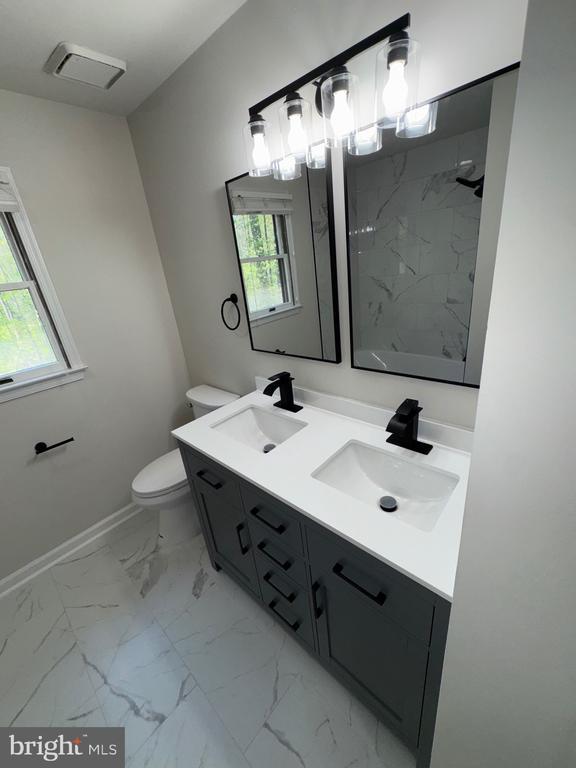 12704 Getty Ln, Spotsylvania, VA 22551 - bathroom with double vanity, a marble finish shower, and marble look tiles