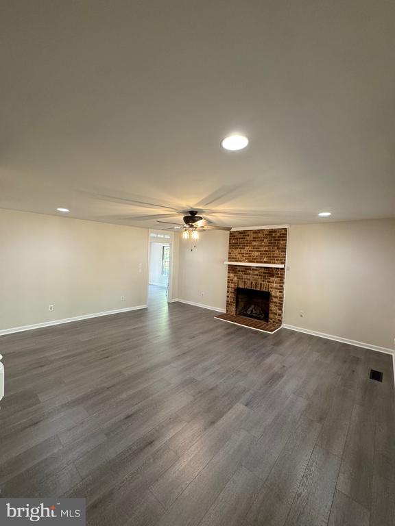 12704 Getty Ln, Spotsylvania, VA 22551 - unfurnished living room featuring a ceiling fan, dark wood-style flooring, a brick fireplace, and recessed lighting