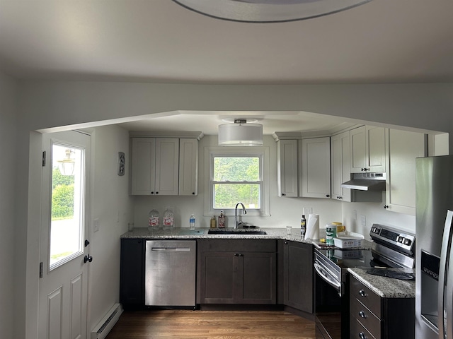 125 Mccutchen School Ln, Goshen, VA 24439 - kitchen with appliances with stainless steel finishes, under cabinet range hood, a baseboard radiator, light stone counters, and dark wood finished floors