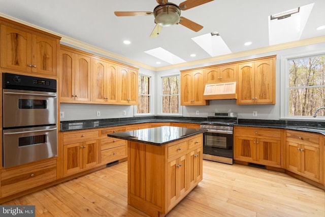  - kitchen with a sink, a skylight, ventilation hood, plenty of natural light, and appliances with stainless steel finishes