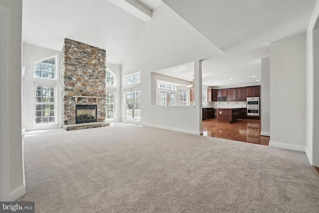 11402 Chivalry Chase Ln, Spotsylvania, VA 22551 - unfurnished living room featuring carpet flooring, healthy amount of natural light, baseboards, a stone fireplace, and a towering ceiling