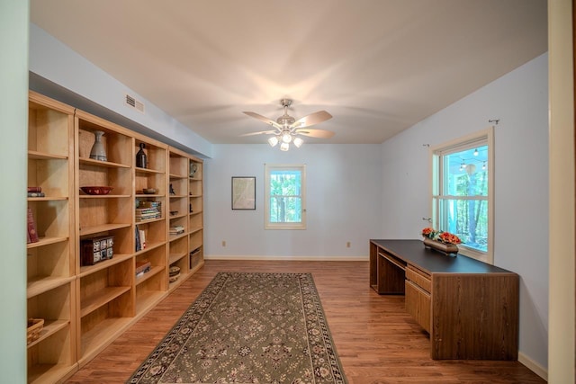 office featuring light wood-type flooring, a ceiling fan, and baseboards