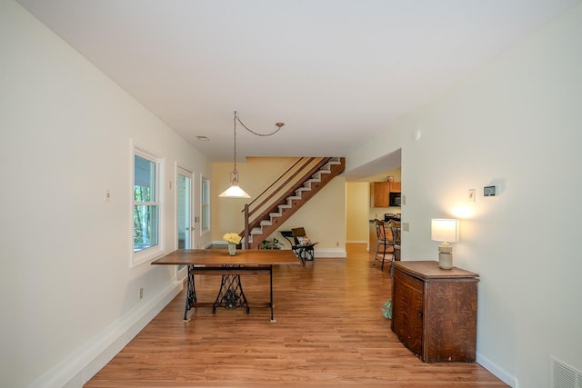 dining space with light wood-style flooring, baseboards, and stairs