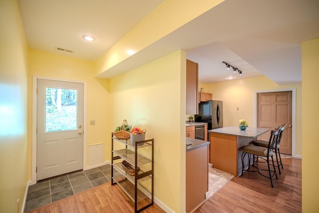 kitchen with freestanding refrigerator, a breakfast bar, a kitchen island, dark wood-style floors, and rail lighting
