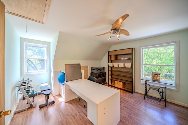 home office featuring attic access, light wood-style floors, ceiling fan, baseboards, and vaulted ceiling