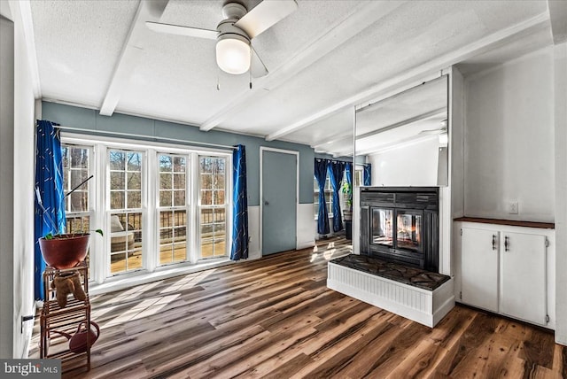 197 Holly Grove Ct, Bumpass, VA 23024 - unfurnished living room featuring beamed ceiling, a ceiling fan, a multi sided fireplace, wood finished floors, and a textured ceiling