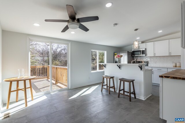 6760 Courthouse Rd, Louisa, VA 23093 - kitchen featuring a breakfast bar area, decorative backsplash, a ceiling fan, a center island, and appliances with stainless steel finishes