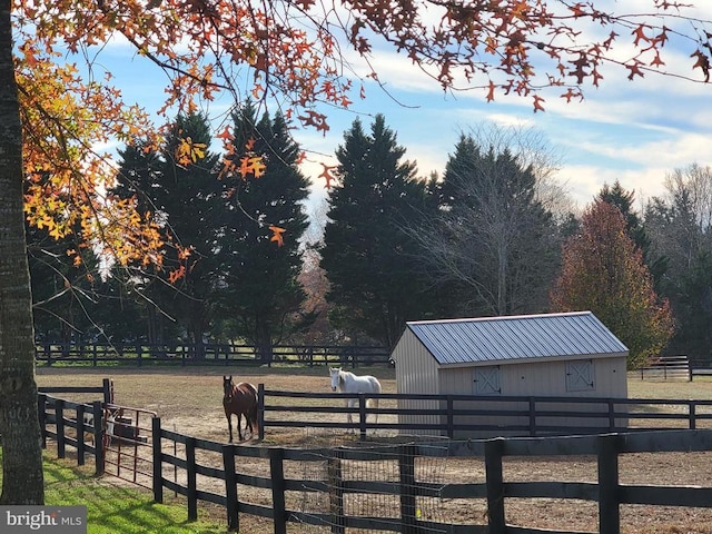 surrounding community with fence, an outbuilding, and a rural view