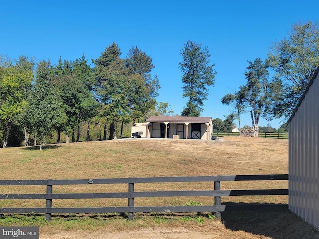 view of yard with an outbuilding, an exterior structure, a view of rural / pastoral area, and fence