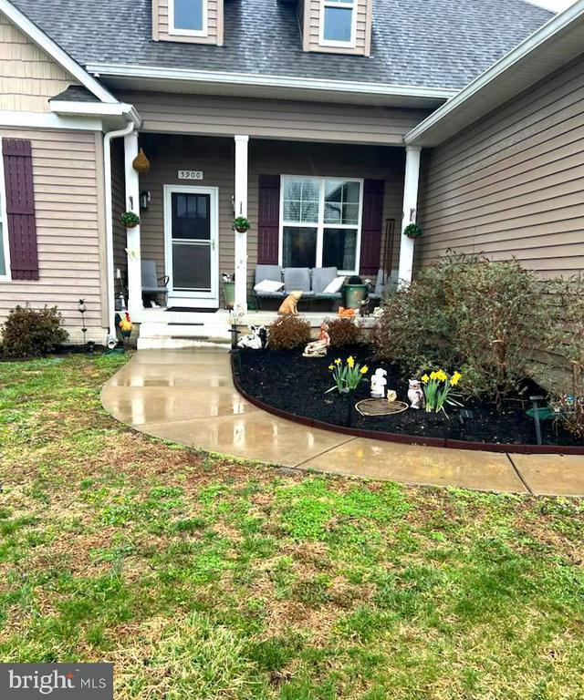 property entrance with roof with shingles, a porch, a yard, and an outdoor living space