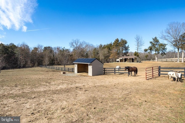 view of yard featuring an exterior structure, an outdoor structure, an enclosed horse arena, and a view of rural / pastoral area