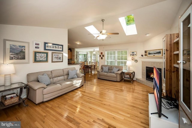 104 Tall Pines Ave, Locust Grove, VA 22508 - living area with ceiling fan, light wood-style floors, a tiled fireplace, and vaulted ceiling with skylight