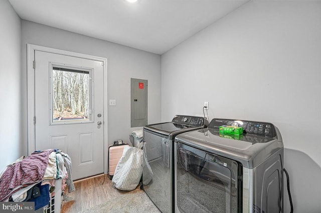 washroom with electric panel, washer and dryer, and wood finished floors