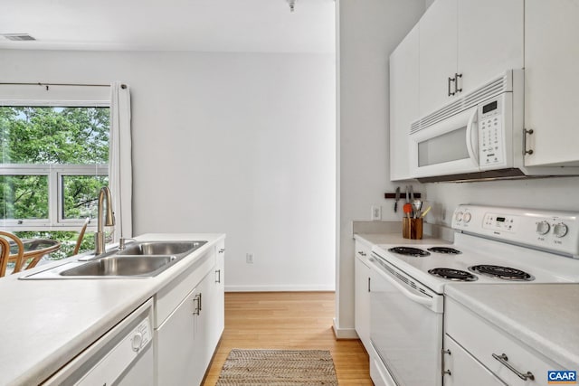 kitchen featuring white appliances, a sink, light wood-style floors, and light countertops