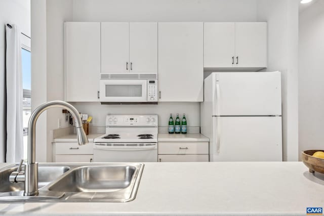 kitchen featuring white appliances, a sink, light countertops, and white cabinets