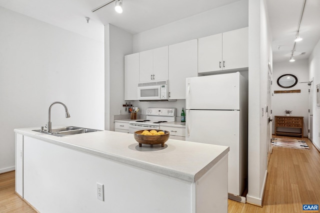 kitchen featuring white appliances, rail lighting, a sink, light wood-style floors, and white cabinetry