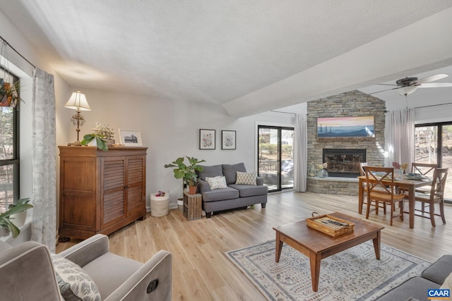 2 Amethyst Rd, Palmyra, VA 22963 - living room featuring a stone fireplace, ceiling fan, vaulted ceiling, light wood-style floors, and a textured ceiling
