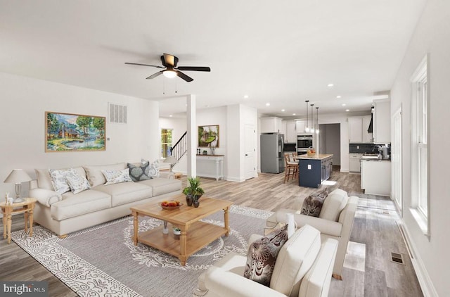  - living area with light wood-style floors, a ceiling fan, stairs, and recessed lighting