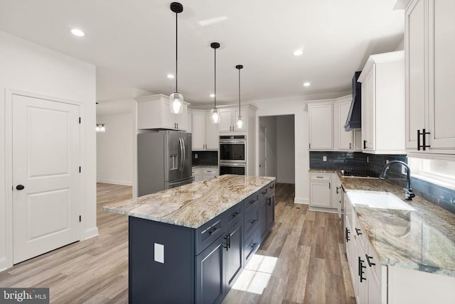  - kitchen featuring stainless steel appliances, white cabinetry, a center island, light wood-style flooring, and decorative backsplash