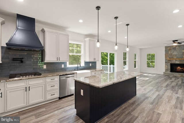  - kitchen with appliances with stainless steel finishes, premium range hood, a sink, ceiling fan, and a fireplace