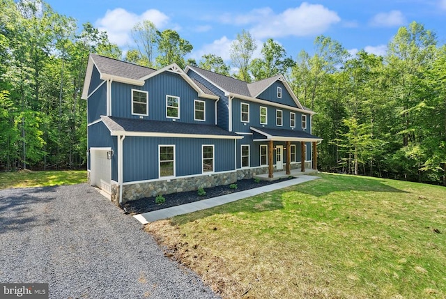  - colonial inspired home with a porch, stone siding, a front lawn, a shingled roof, and gravel driveway