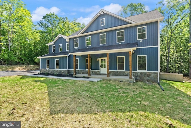  - view of front of house with stone siding, a front lawn, and roof with shingles