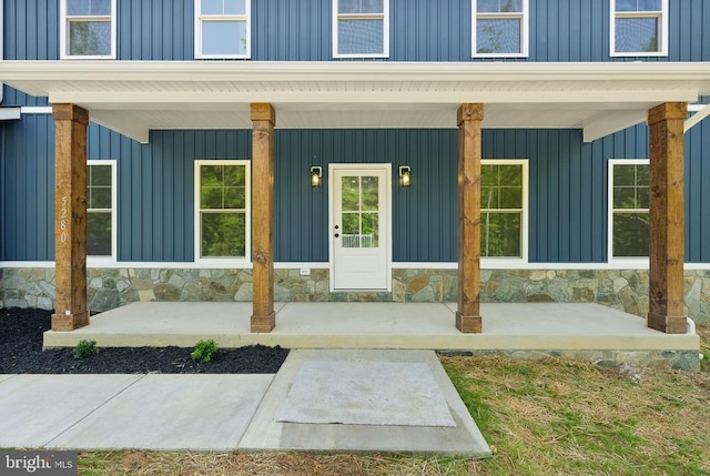  - entrance to property featuring board and batten siding, stone siding, and covered porch