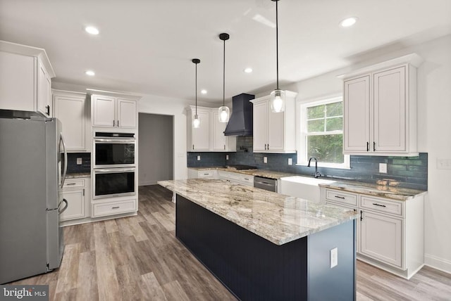  - kitchen with appliances with stainless steel finishes, wall chimney exhaust hood, decorative backsplash, white cabinets, and recessed lighting