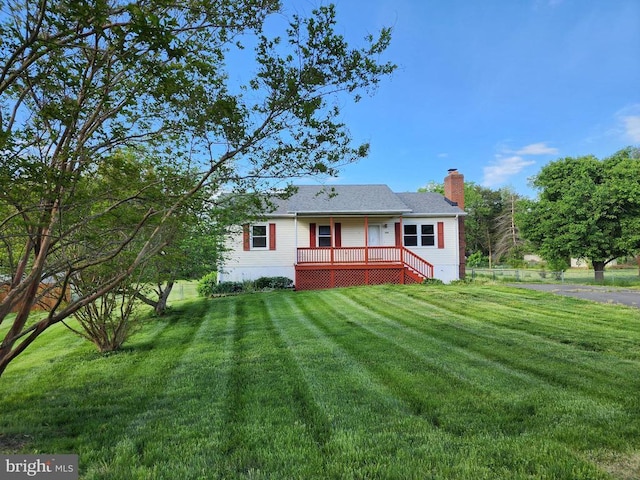 rear view of house featuring a lawn, a chimney, and a deck