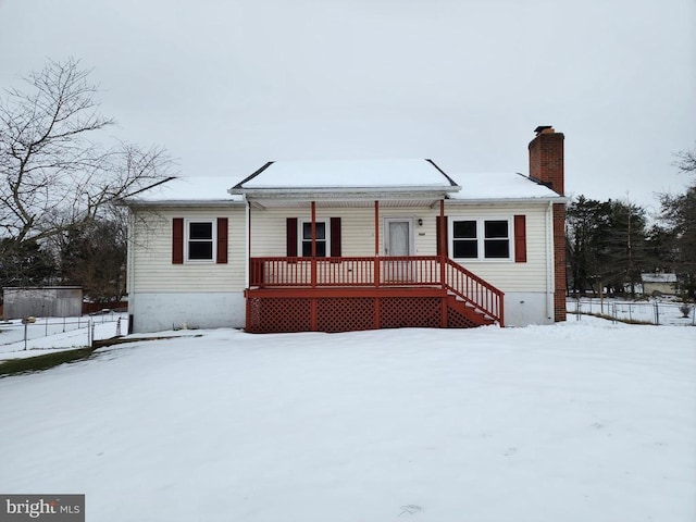 view of front of house featuring a chimney, stairs, covered porch, and fence