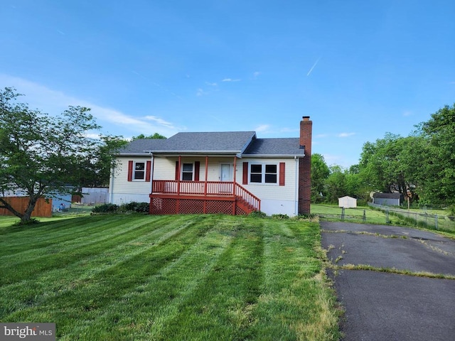 bungalow with a porch, a front lawn, fence, and a chimney