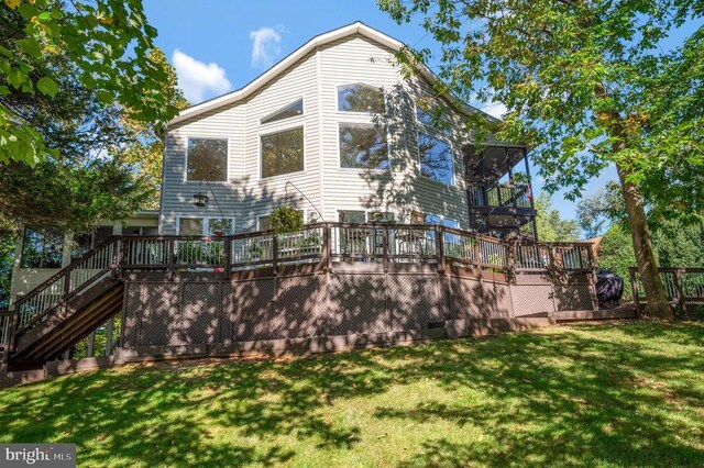 back of house with a deck, stairs, and a lawn