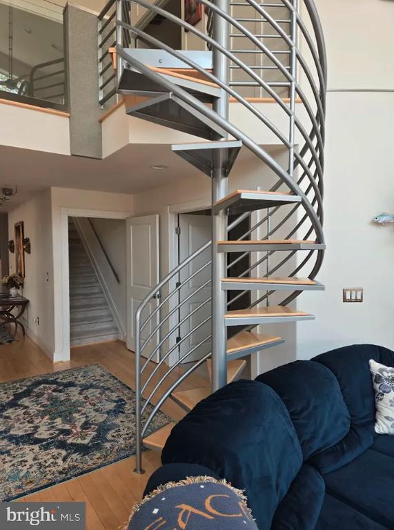 stairs featuring wood finished floors, a towering ceiling, and baseboards