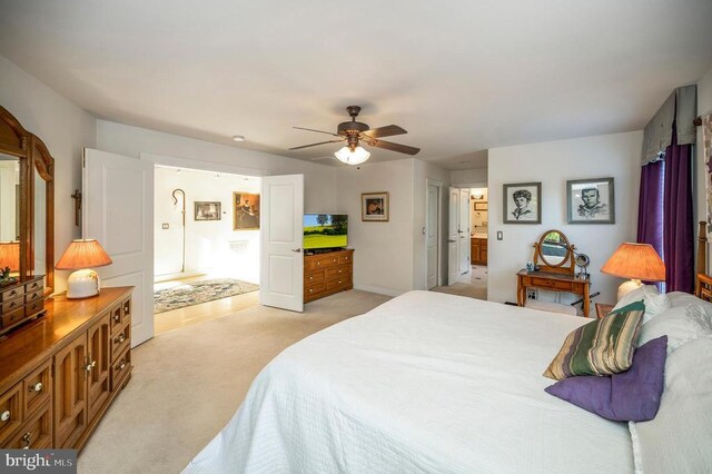 bedroom featuring light carpet, a ceiling fan, and ensuite bath