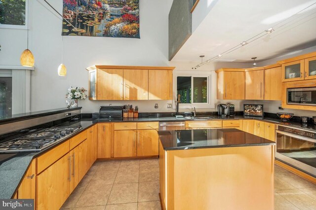 kitchen featuring stainless steel appliances, light tile patterned floors, a sink, and decorative light fixtures