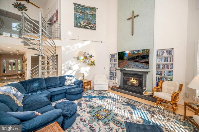 living room with a high ceiling, a glass covered fireplace, plenty of natural light, and stairway