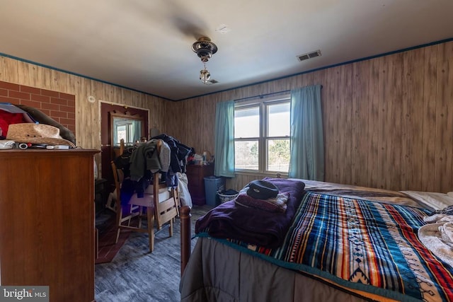 bedroom featuring visible vents, dark wood finished floors, and wooden walls