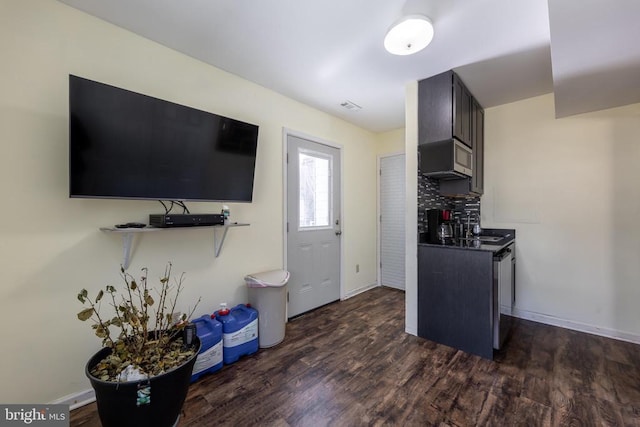 kitchen with dark wood-type flooring, visible vents, dark brown cabinets, backsplash, and dark countertops