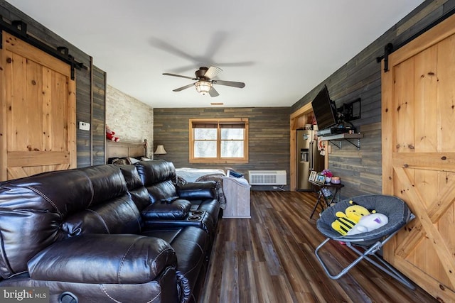 living room with ceiling fan, a barn door, and dark wood-type flooring