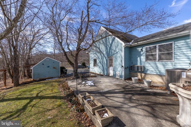 view of side of home with central air condition unit, a lawn, and a patio