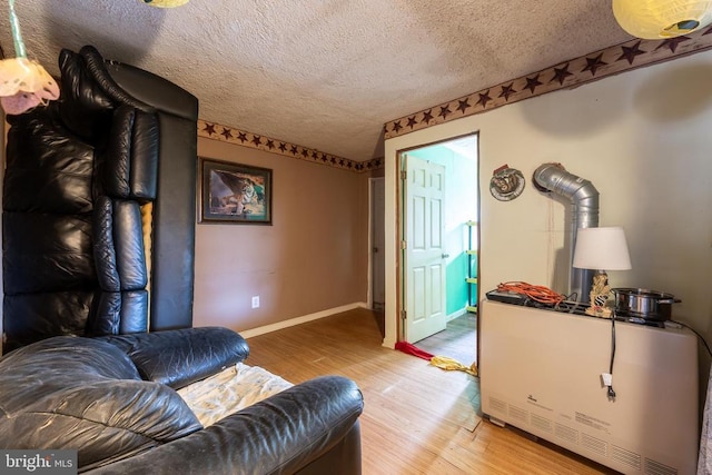 sitting room featuring a textured ceiling, baseboards, and wood finished floors