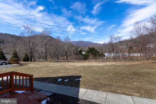 view of yard featuring a rural view, fence, and a mountain view