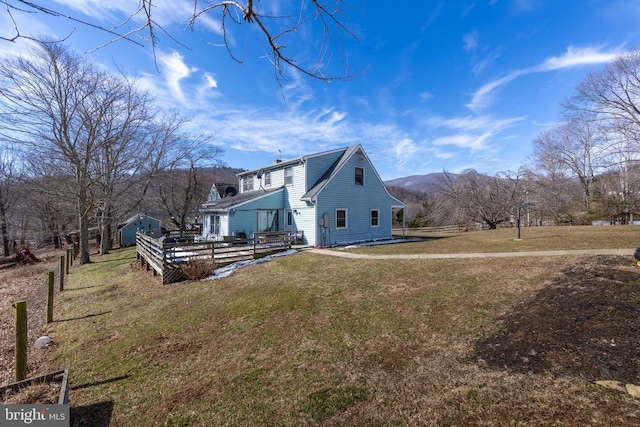 view of side of home featuring a deck with mountain view and a lawn