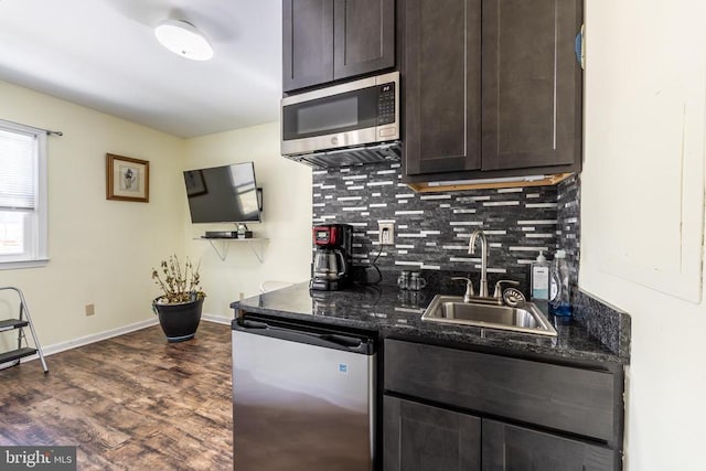 kitchen with dishwashing machine, a sink, dark brown cabinets, stainless steel microwave, and dark stone countertops