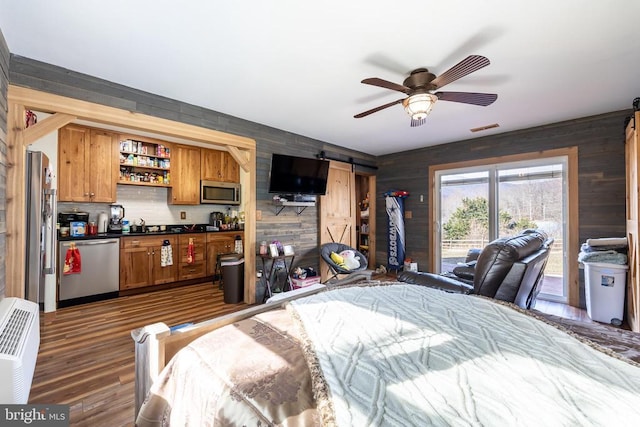 bedroom with access to exterior, dark wood finished floors, visible vents, a barn door, and stainless steel refrigerator